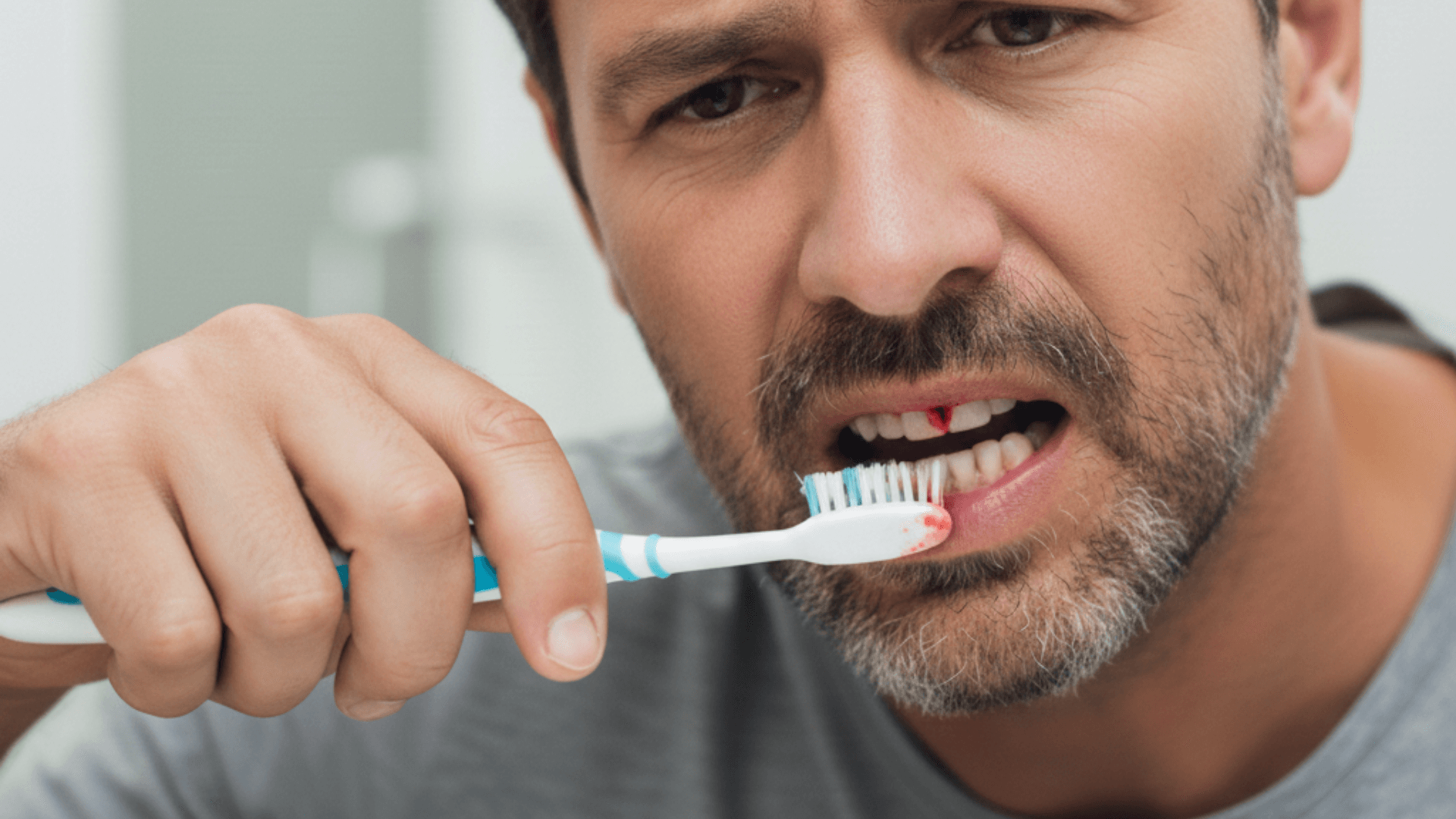 Persona mirándose en el espejo comprobando el sangrado de sus encías tras el cepillado dental.