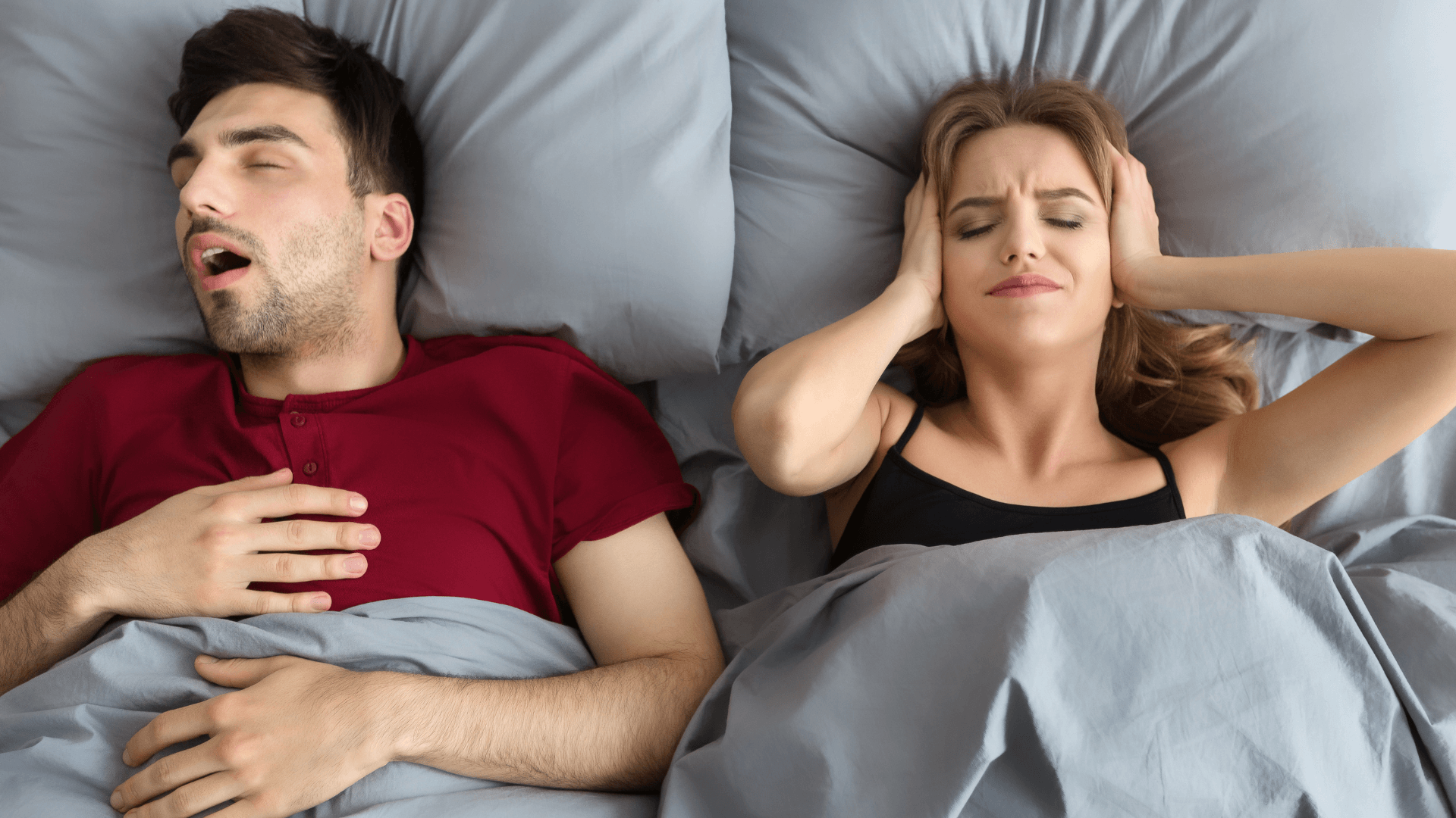 Pareja durmiendo; el hombre ronca mientras la mujer permanece despierta por el ruido, posible señal de ronquidos o apnea del sueño.